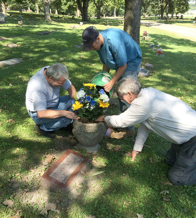 Will with a volunteer and an employee digging the flowers into the urn