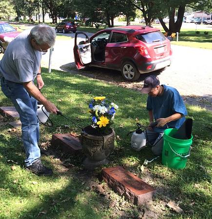 A volunteer and an employee cleaning the gravestones.